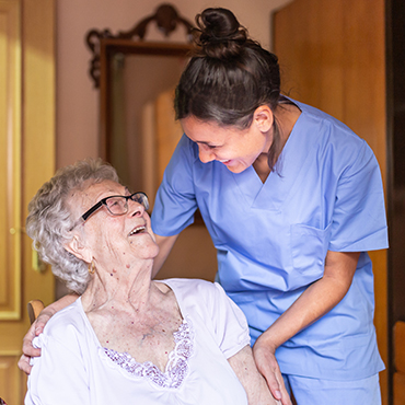 A nurse assisting an elderly woman in a wheelchair, providing care and support with compassion and expertise.