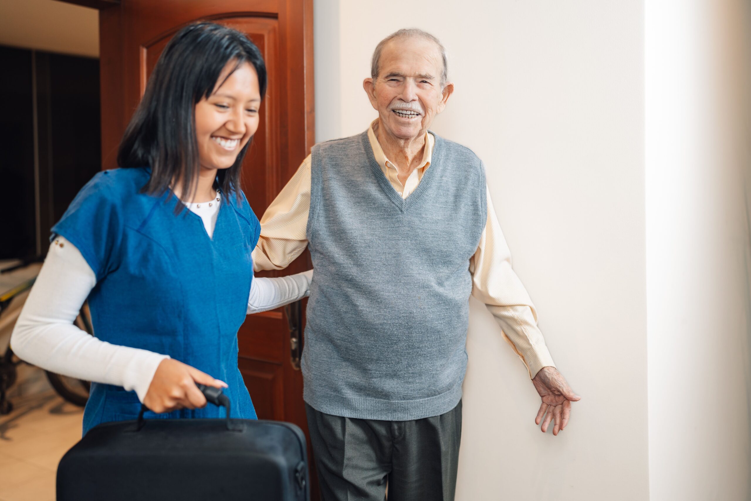 A woman and an older man smiling warmly at each other, showing a genuine connection and happiness.